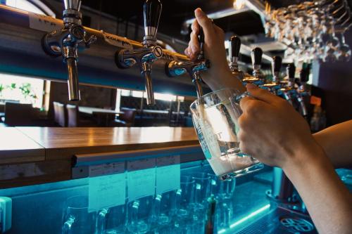 a person is drinking from a glass at a bar at Legnicki Browar Książęcy Hotel i Restauracja in Legnica