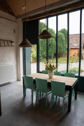 a dining room with a table and chairs and windows at La Dame Jeanne in Brakel