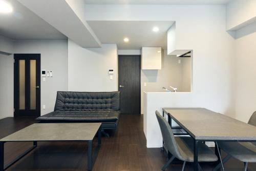 a dining room with two tables and a couch at Vacation Rental Hotel TENMONKAN in Kagoshima