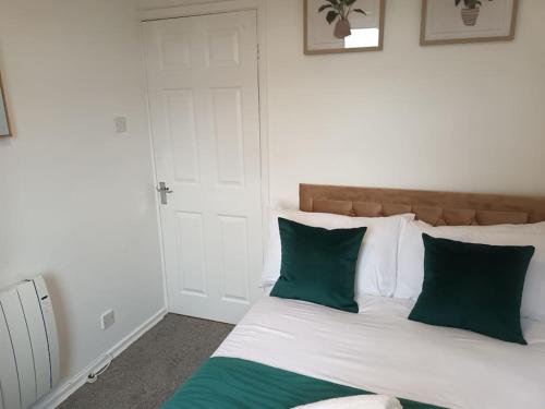 a bedroom with a bed with green and white pillows at Jedid Kings Heath Apartment in Birmingham
