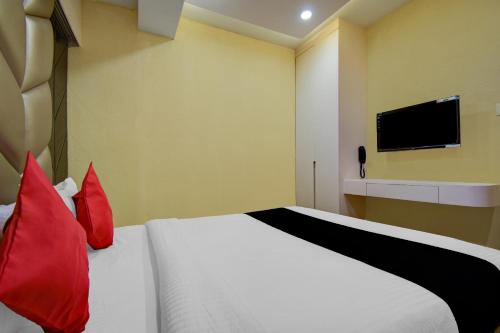 a bedroom with a bed with red pillows and a tv at Super Collection O Snowfox in Kolkata