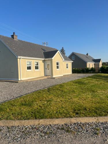a large yellow house on a gravel driveway at Cúlú in Kincasslagh