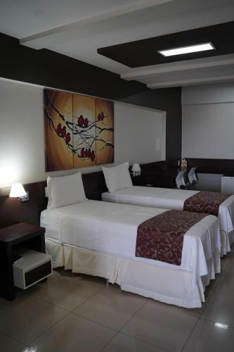 two beds in a hotel room with white sheets at Residence Hotel Imperatriz in Imperatriz