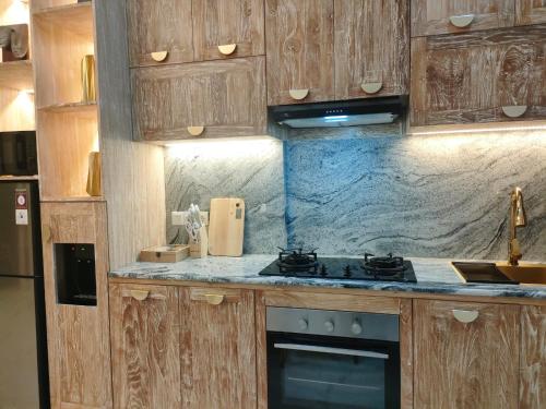 ウルワツにあるVilla Emas Mulia Uluwatu Luxury 6の木製のキャビネットとコンロ付きオーブンを備えたキッチン