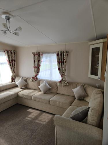 a living room with a couch and windows at Lytham Luxe 6 Birth Caravan in Weeton