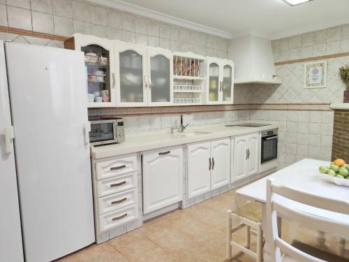Una cocina con gabinetes blancos y un refrigerador blanco. en Casa Aguilar, en Ronda