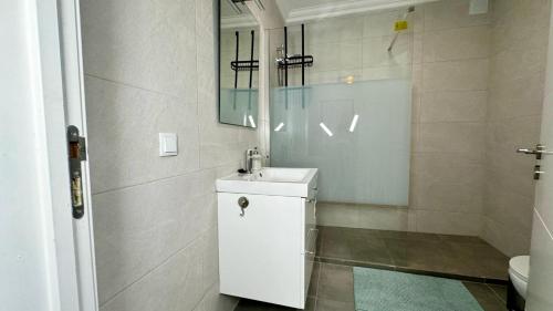 ein weißes Badezimmer mit Waschbecken und Spiegel in der Unterkunft Cozy Apartment in Sagres in Sagres