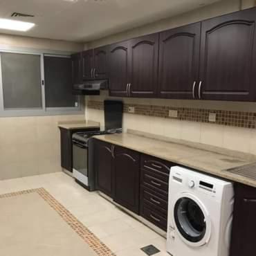 a kitchen with dark cabinets and a washer and dryer at SN REAL ESTATE HOME in Abu Dhabi