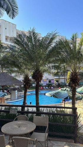 a pool with palm trees and tables and chairs at thermasparadise Rio quente in Rio Quente