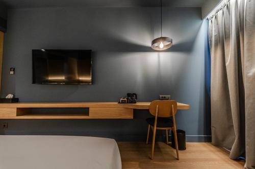a bedroom with a desk and a tv on a wall at Magnes Hotel in Volos