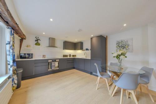 a kitchen with a glass table and blue cabinets at Luxury Character Apartment St Albans By Central Stays Short Lets & Serviced Accommodation With Free Parking in St. Albans