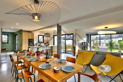une salle à manger avec une grande table en bois et des chaises jaunes dans l'établissement LocaLise - M14 - Caligourdaine - Maison d'exception - Construction de 2024 - à 30m de la mer et quelques pas des plages - extérieur clos - 4 places de parking privatives - wifi inclus - draps inclus - centre et port à 7 minutes à pied, au Guilvinec