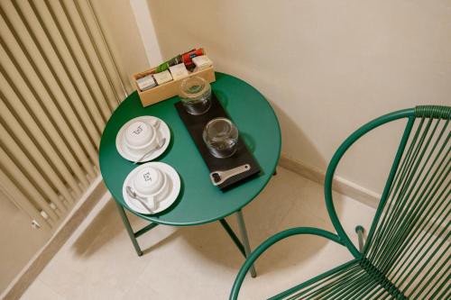 a green table with plates and glasses and a chair at Palazzo Patrizi Suites & Spa in Siena