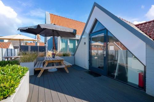 a wooden deck with a table and an umbrella at Weststraat 22 - Ouddorp - Appartement Oost 3P in Ouddorp