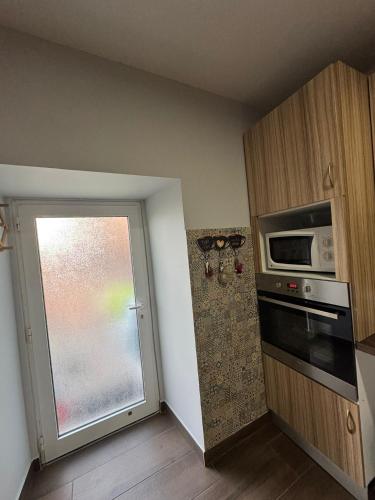 a kitchen with a microwave and a door with a window at Sofiamarholidays O Cantinho da Avó Bina in Moita