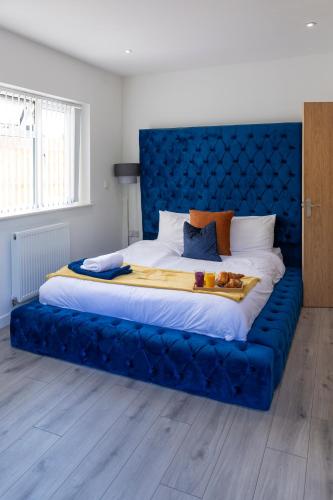 a large bed with a blue headboard in a room at 2 minutes walk to JR & Manor Hospitals , Close to Oxford Brookes University Bluebird Apartment in Oxford