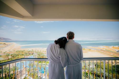 a couple standing on a balcony looking at the ocean at David Dead Sea Resort & Spa in Ein Bokek
