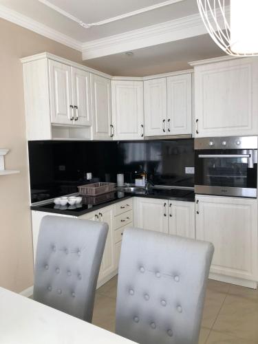 a white kitchen with white cabinets and black appliances at Zlatibor Hills Star Wellness & Spa in Zlatibor