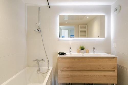 une salle de bain avec un lavabo, un miroir et une baignoire dans l'établissement Newly Built Apartment with Pool, Walk to the Beach, à Antibes