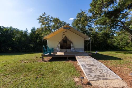 a tent in a field with a wooden platform at Khushatta Hills Ranch Glamping - Mom Mollie in Coldspring