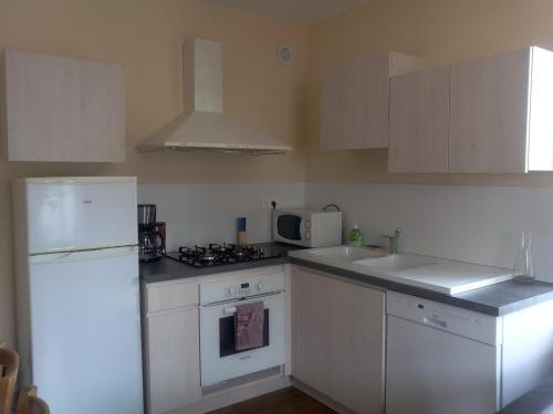 Il comprend une cuisine équipée d'appareils électroménagers blancs et d'un réfrigérateur blanc. dans l'établissement Gite les Granites à moins de 100m du lac, à Gérardmer