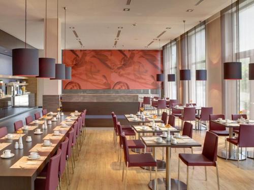 a dining room with long tables and purple chairs at IntercityHotel Leipzig in Leipzig