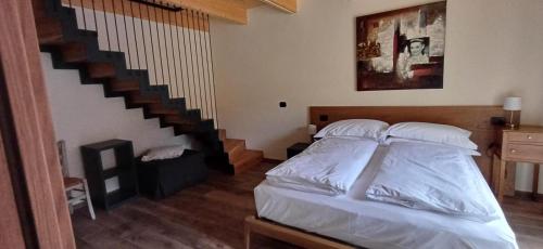a bedroom with a bed with white sheets and a staircase at B&B Piccolo Relais in Lessolo