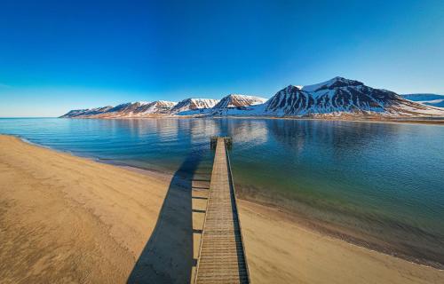 a boardwalk on a beach with a mountain in the background at Holt Inn in Flateyri