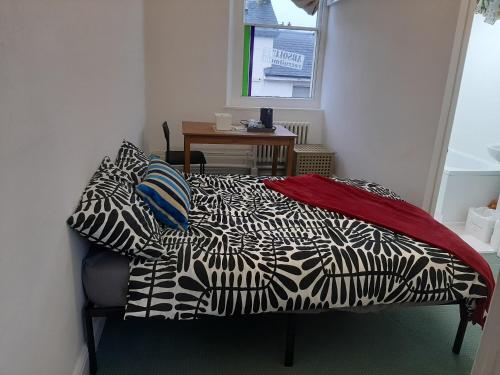 a bedroom with a bed with a black and white comforter at Newport Ensuite Sleeps 2 near Train Station in Newport