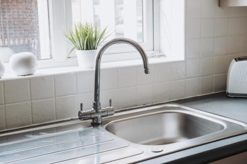 a kitchen sink with a faucet next to a window at Modern & Comfortable with Free Parking in Bedford