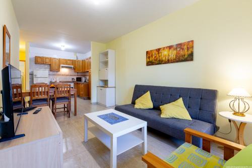 a living room with a blue couch and a kitchen at 2B Apartamento Abrigos, Wifi y balcón in Los Abrigos