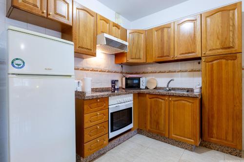 a kitchen with wooden cabinets and a white refrigerator at 2B Apartamento Abrigos, Wifi y balcón in Los Abrigos