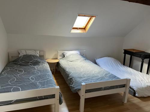 deux lits dans une petite pièce avec une fenêtre dans l'établissement Charmante amiénoise proche gare, à Amiens