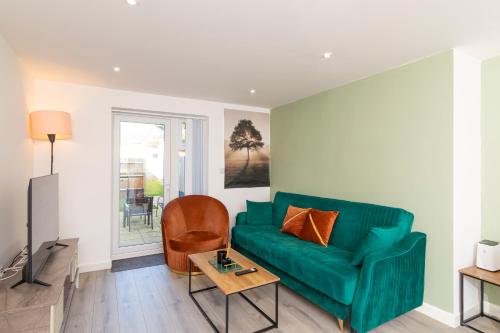 a living room with a green couch and a table at The Phantom Apartment 1 minute walk to JR, Churchill Manor Nuffield Hospitals Oxford B Uni, Sleeps 5 Guests comfortably very modern 2 rooms 3 bathrooms Private Garden in Oxford