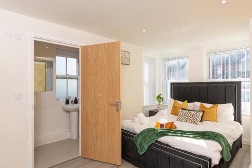 a bedroom with a large bed with yellow pillows at The Phantom Apartment 1 minute walk to JR, Churchill Manor Nuffield Hospitals Oxford B Uni, Sleeps 5 Guests comfortably very modern 2 rooms 3 bathrooms Private Garden in Oxford