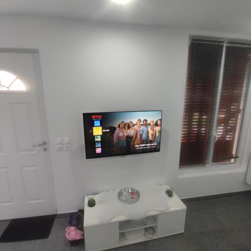 Elle comprend une télévision à écran plat suspendue sur un mur blanc. dans l'établissement Petite maison avec jardin, à Montluçon