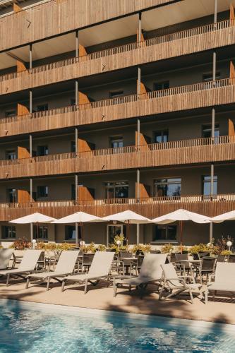 a hotel with lounge chairs and a swimming pool at Hotel Valaisia Crans Montana, a Faern Collection Resort in Crans-Montana