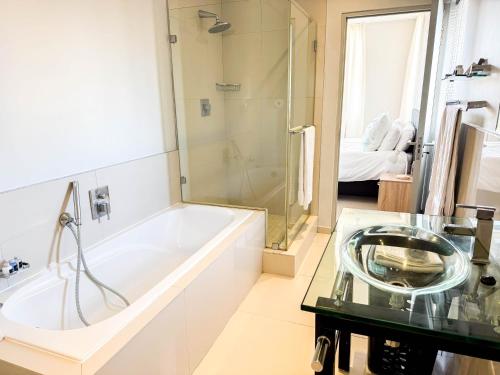 a bathroom with a tub and a sink and a shower at Ilanga Africa Beach Front Apartments in Cape Town