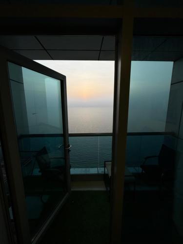 a room with a view of the ocean from a balcony at Sunset Beach View Holiday Homes in Ajman 