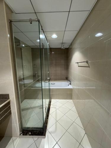 a bathroom with a glass shower and a tub at Sunset Beach View Holiday Homes in Ajman 