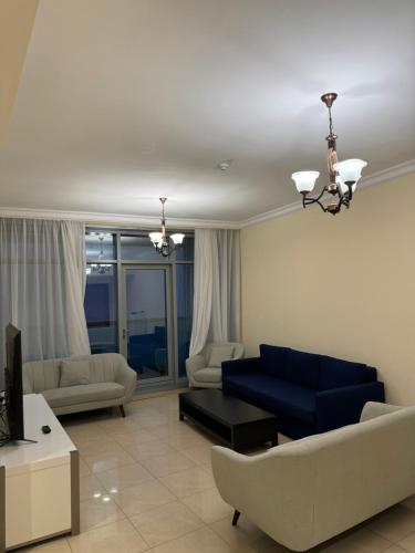 a living room with a blue couch and a tv at Sunset Beach View Holiday Homes in Ajman 