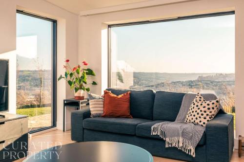 a living room with a blue couch and a large window at Stunning 5 Bedroom New Build with Amazing Views! in Bath
