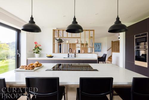 a kitchen with black pendant lights above a kitchen island at Stunning 5 Bedroom New Build with Amazing Views! in Bath