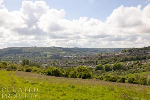 a green hillside with a city in the distance at Stunning 5 Bedroom New Build with Amazing Views! in Bath