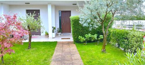 a house with a green yard with trees and a pathway at Villa Green Harmony in Bussolengo