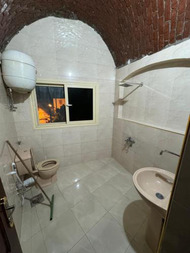 a bathroom with a toilet and a sink and a window at Nubian Dreams Guest House in Aswan