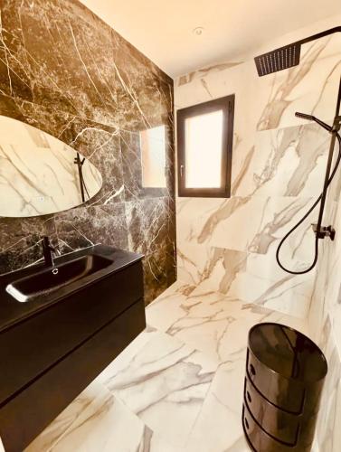La salle de bains est pourvue d'un lavabo noir et de murs en marbre. dans l'établissement Villa Casa Maredda bord de mer avec piscine, à Palasca