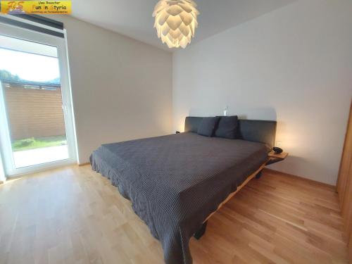 a bedroom with a large bed and a chandelier at Apartment Bergzeit in Öblarn