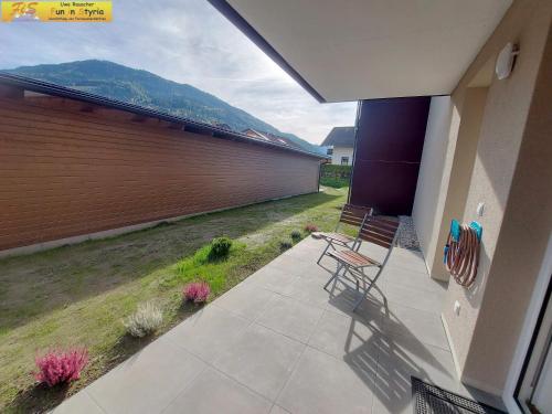 a patio with two chairs and a fence with a mountain at Apartment Bergzeit in Öblarn