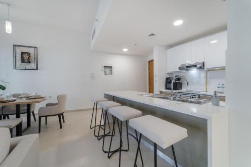 a kitchen with a bar with stools and a table at Free housekeeping visits during your stay - StayShort - Restful 1-Bedroom Apartment at Al Andalus in Jumeirah Golf Estates in Dubai